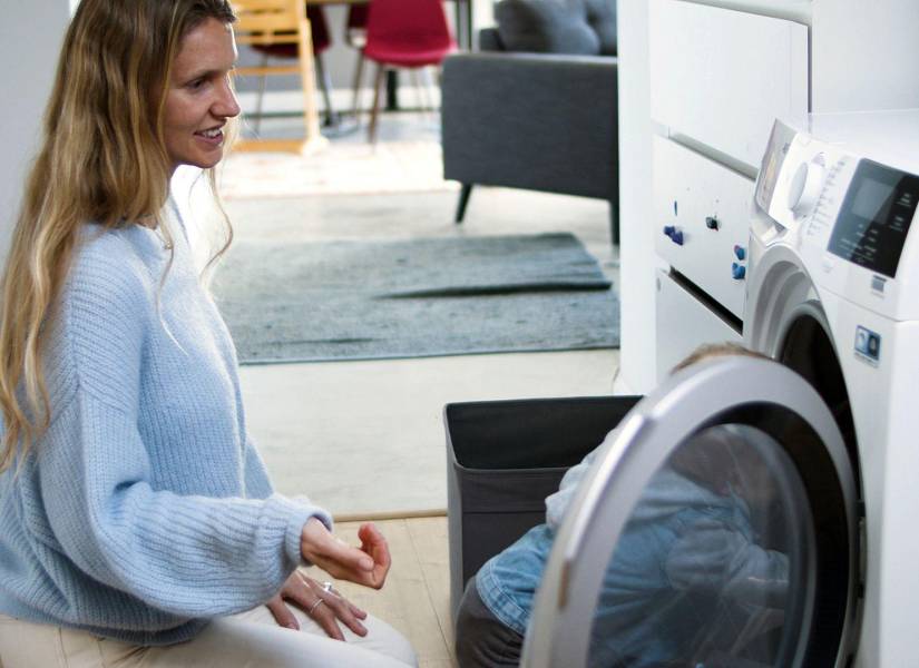 Imagen referencial: Mujer colocando sábanas en la lavadora.