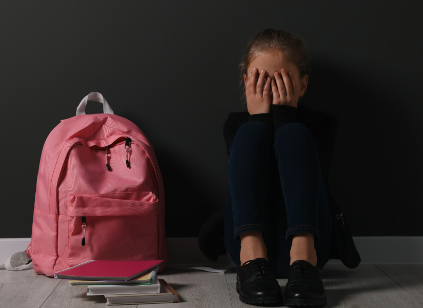 Foto referencial de una estudiante llorando junto a su mochila