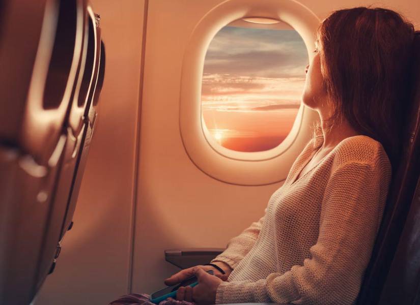 Imagen referencial de mujer viendo por la ventana en el avión.