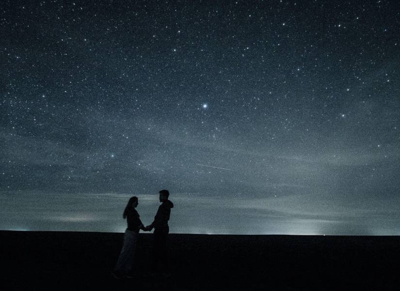 Imagen referencial de pareja bajo cielo nocturno estrellado.