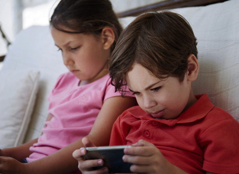 Foto referencial de dos niños utilizando el celular