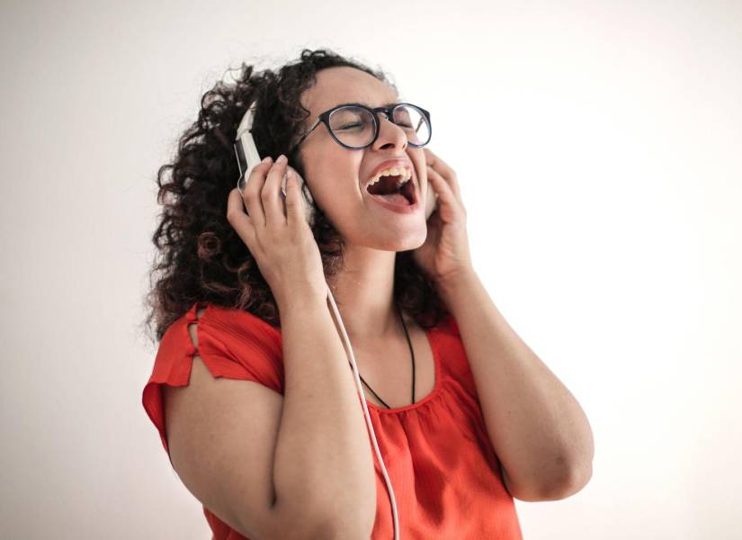 Imagen referencial: Mujer usando auriculares y cantando.