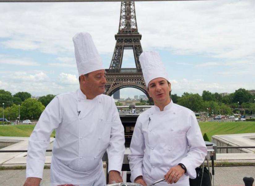 Chefs cocinando con la Torre Eiffel a sus espaldas.