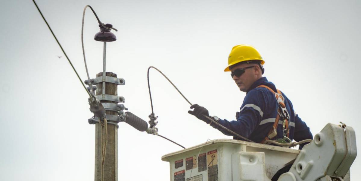 Un obrero realiza trabajos de mantenimiento junto a un poste de alumbrado público.