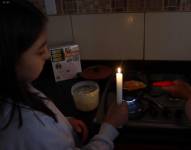 Imagen de una chica encendiendo una hornilla de cocina con una vela, ante los cortes de energía.