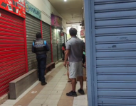 Imagen de un agente de tránsito y un ciudadano observando la escena de crimen en un centro comercial de La Libertad, Santa Elena.