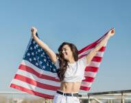 Imagen referencial de mujer sosteniendo la bandera de Estados Unidos.