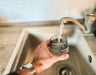 Imagen de un hombre llenando un vaso de agua de la llave.