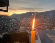 Una vela encendida con el fondo del Centro Histórico de Quito.