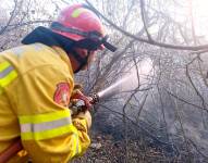 Imagen de un bombero lanzando agua a un foco de incendio, en Guayaquil.