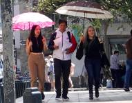 Ciudadanos usan sombrillas para protegerse del sol, en Cuenca.