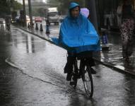 Un ciclista circula bajo un chaparrón en Pekín, China