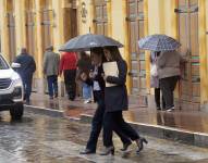 Imagen referencial de persona cubriéndose de la lluvia en Cuenca.