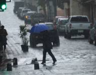 Mujer con paraguas caminando en la calle.