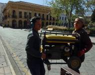 Imagen de archivo de dos hombres cargando un generador eléctrico en Cuenca.