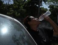 Una mujer se hidrata ante el intenso calor en Guayaquil.