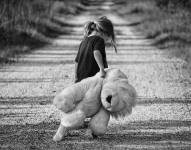 En la imagen se observa a una niña caminando en una carretera junto a su muñeco.
