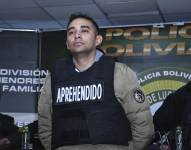 Un agente de la Dirección de Análisis Criminal e Inteligencia (DACI) de Bolivia escolta al capitán de infantería Miguel Burgos este viernes, durante su presentación luego de su arresto en La Paz.