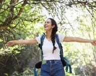 Imagen de referencial de mujer explorando feliz al aire libre.