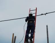 Imagen de un empleado de CNEL durante un trabajo de mantenimiento y cambio de cable.