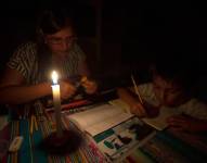 Una madre y su hijo estudian a la luz de la vela en Quito, ante los apagones.