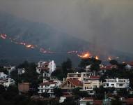 Un incendio se acerca a las casas en el monte Penteli, en el noreste de Grecia, este lunes.