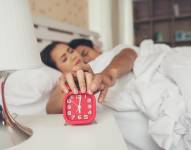 Despertador rojo con pareja durmiendo