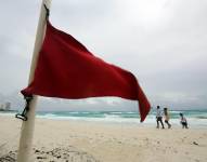 Turistas caminan por una playa con alto oleaje debido a la tormenta tropical Helen