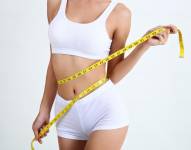 Mujer midiendo su cintura con cinta métrica tras pérdida de peso.