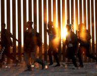 Fotografía de archivo de migrantes que caminan junto al muro en la frontera de EE.UU., y México en Lukeville, Arizona, el 12 de diciembre de 2023.