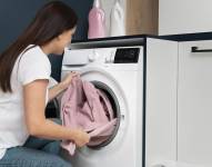 Imagen referencial de mujer metiendo ropa a la lavadora.