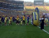 Jugadores de Barcelona SC y Emelec ingresan al campo de jugeo en el estadio Monumental