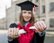 Imagen referencial de mujer sosteniendo su título universitario en su graduación.