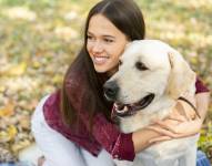 Imagen referencial de mujer abrazando a su perro, viendo al horizonte.