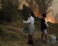 Personas intentan apagar un incendio con baldes de agua este martes, en Quito (Ecuador). EFE/ Santiago Fernández