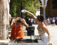 Dos mujeres se refrescan en una fuente del Patio de los Naranjos de la Mezquita Catedral de Córdoba.