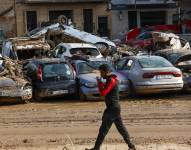 Un hombre camina junto a los coches apilados en Catarroja, Valencia, este martes, una de las localidades más afectados por las inundaciones.