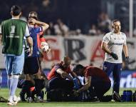 Juan Izquierdo (abajo) de Nacional es atendido por personal de la salud este jueves, en el partido de vuelta de octavos de final de la Copa Libertadores