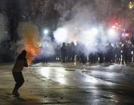 Partidarios de la oposición georgiana lanzan fuegos artificiales hacia la policía durante una protesta frente al edificio del Parlamento en Tbilisi.