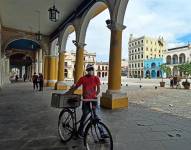 Fotografía de archivo en donde se ve a un hombre que camina con su bicicleta por los portales de una plaza en Cuba. EFE/ Ernesto Mastrascusa