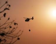 Imagen de helicóptero Arpía Ala 21 de la FAE con sistema bambi bucket combatiendo las llamas desde el aire, en la zona del Cerro Azul en Guayaquil, este lunes 2 de diciembre.