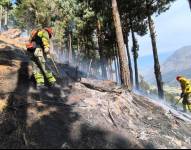 Los bomberos apagando el fuego en un incendio reportado en Cuenca, la capital del Azuay.