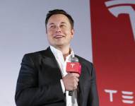Elon Musk junto al logo de Tesla.