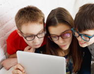 Imagen referencial de niños usando lentes frente a una tablet.