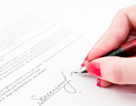 Imagen referencial de mujer firmando un documento.