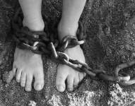 En la imagen se ve a una persona secuestrada, con cadenas en los pies.