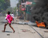 Una mujer que lleva a un niño huye del área después de que se escucharon disparos en Puerto Príncipe, Haití, el 20 de marzo de 2024.