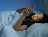 Imagen referencial: Mujer usando su celular antes de dormir.