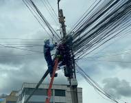 Un obrero acomodando los cables colgados en uno de los postes de la avenida Mariana de Jesús.