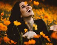 Imagen referencial: Mujer feliz en campo de flores.